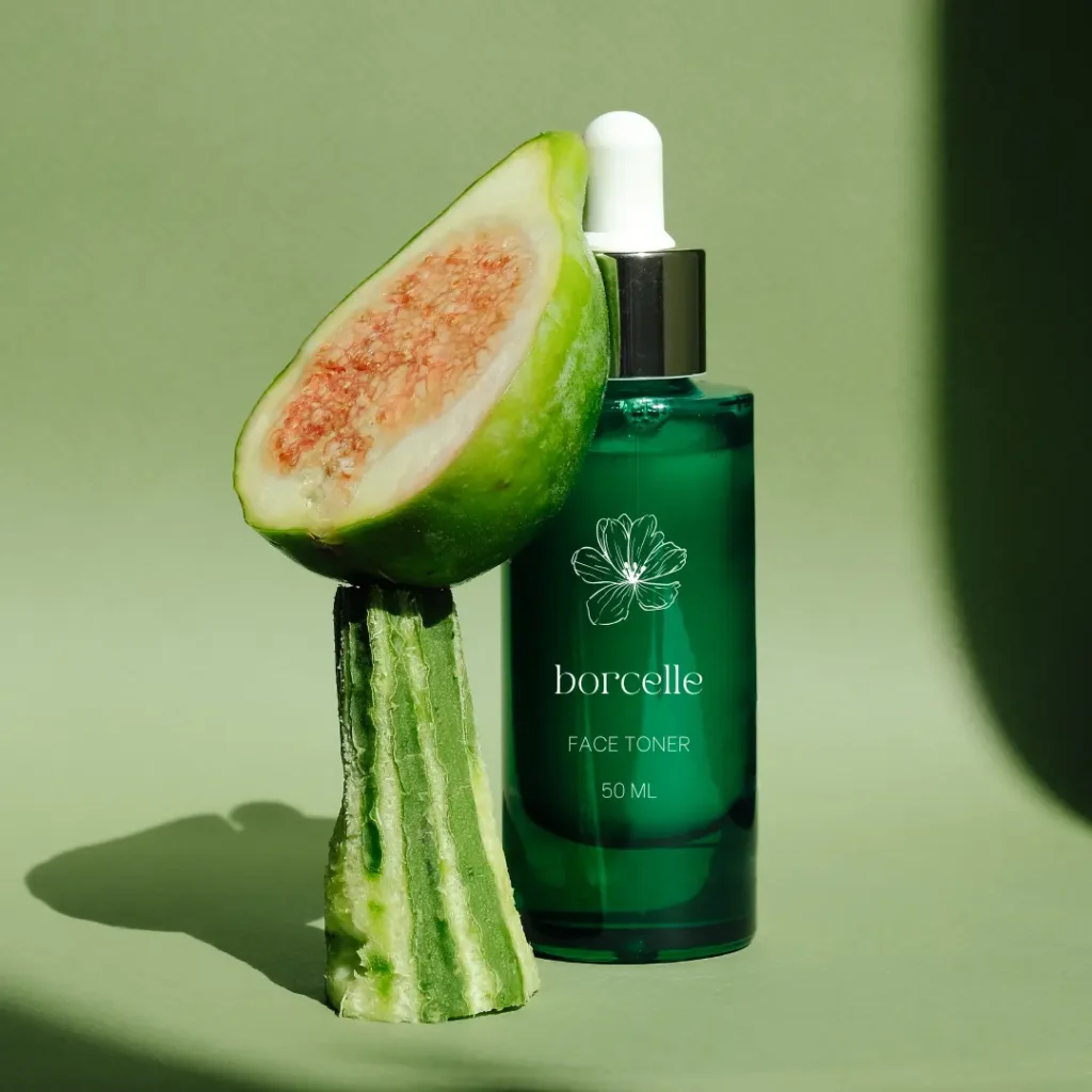 Natural skincare product with a green face toner bottle and a fig displayed on a green background.